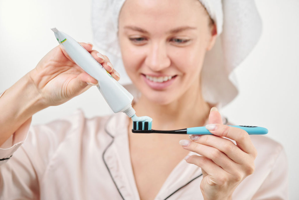 femeie care pregateste pasta si periuta de dinti pentru un periaj corect