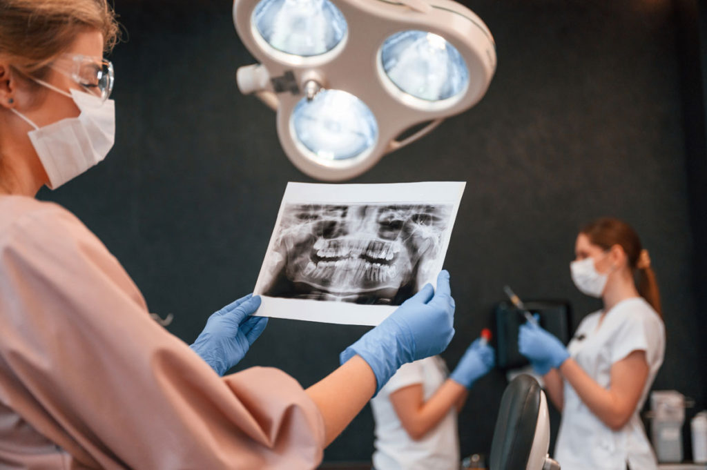 medic dentist analizand o radiografie dentara in vederea reconstructiei dintiilor