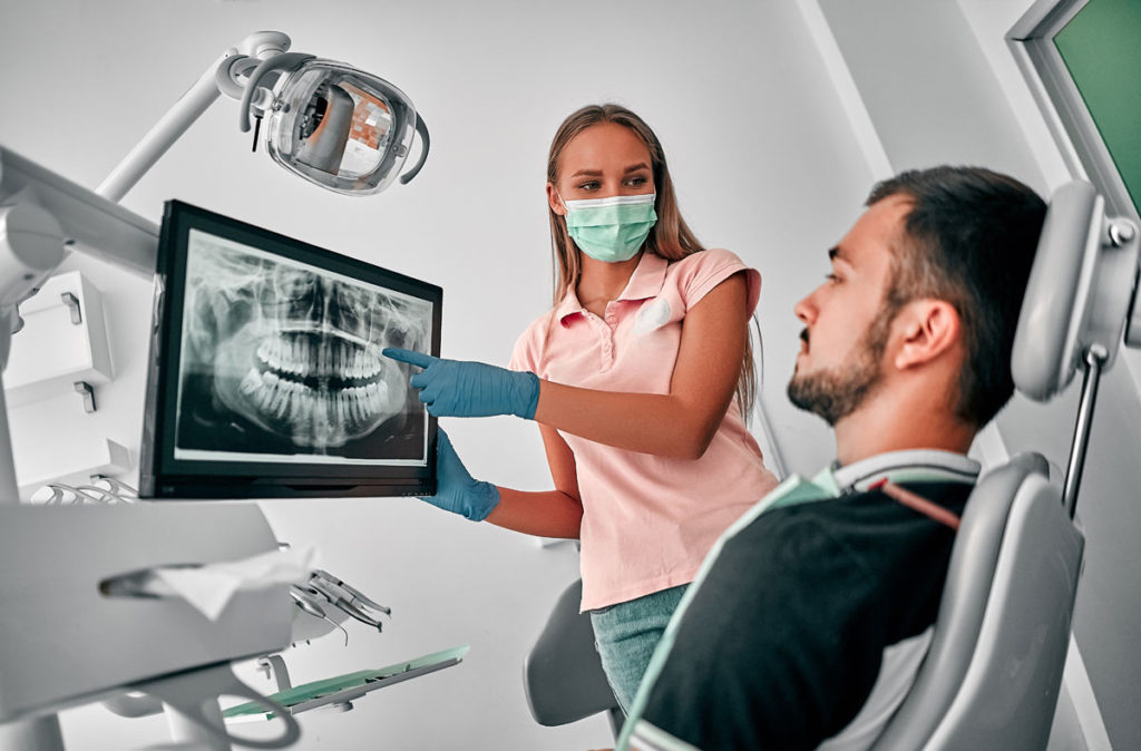 stomatolog explicand pacientului diagnosticul pe o radiografie panoramica